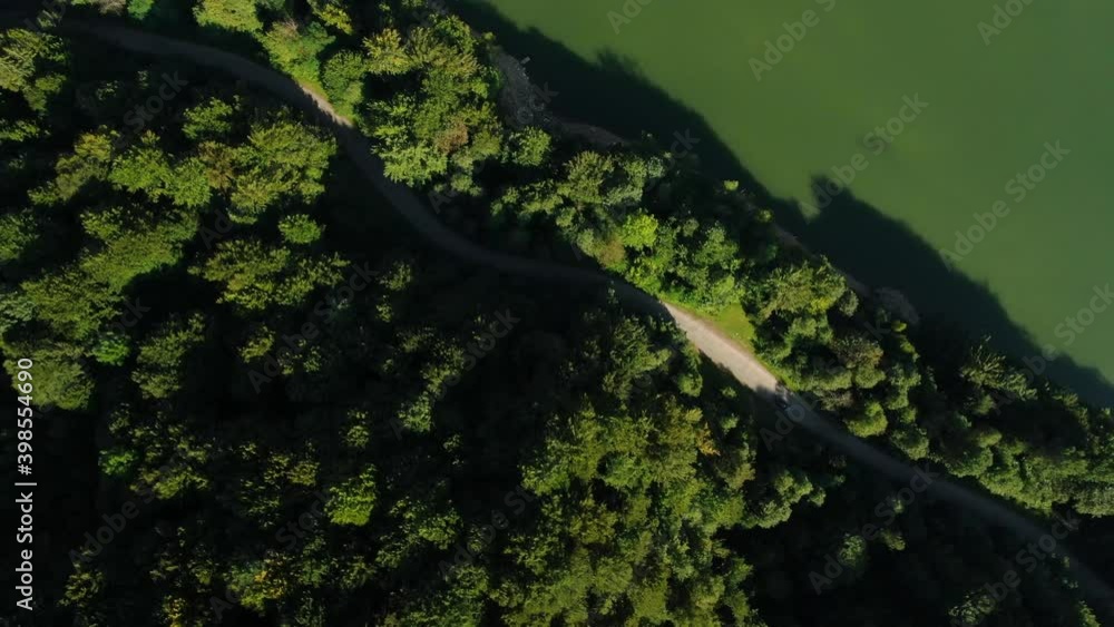 Aerial view of car driving through the fores and the lake on the side. Beautiful mountain road. Driving on the mountain road. Road trip. Mountain forest lake landscape. Car driving through pine forest Aerial view of car driving through the fores and the lake on the side. Beautiful mountain road. Driving on the mountain road. Road trip. Mountain forest lake landscape. Car driving through pine forest