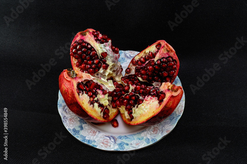 Sliced ripe juicy pomegranate in a bowl on a black background photo