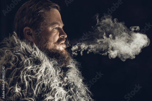 Solid bearded man dressed in a fur mantle exhaling vapour