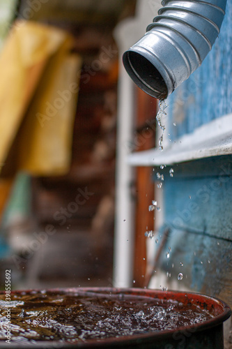 drops of water flow down the drainpipe into the barrel