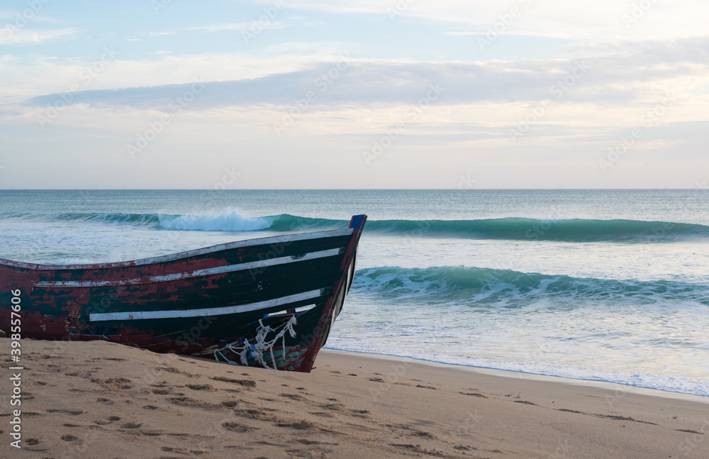Waves breaking behind abandoned patera boat at the beach of Mangueta in Andalusia