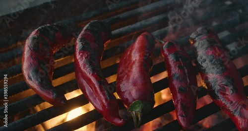 Pan over red chile peppers roasting on a grill. The hot fresh chili peppers cook on an iron grate of a park grill. Hatch red Chile is a staple of New Mexican cuisine and cooking.