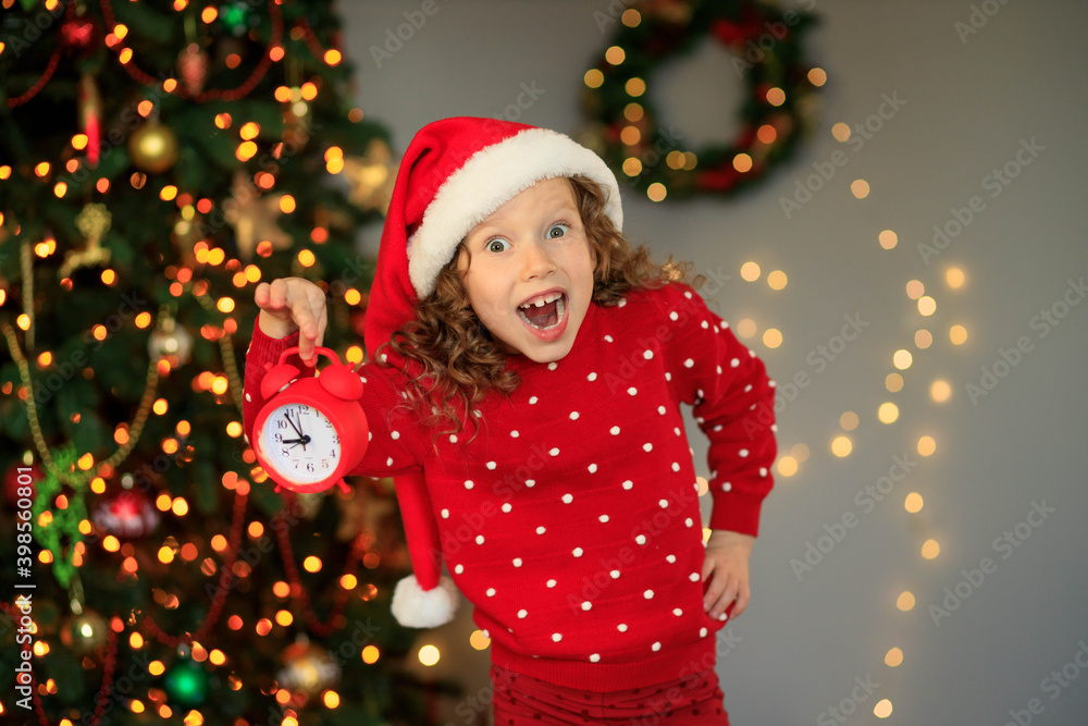 Happy cute girl waiting for the new year with an audio clock in her hands Happy cute girl waiting for the new year with an audio clock in her hands