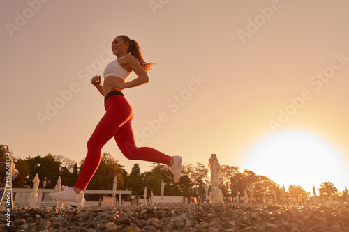 Beautiful sportive woman silhouette in sportswear jogging in the morning dawn