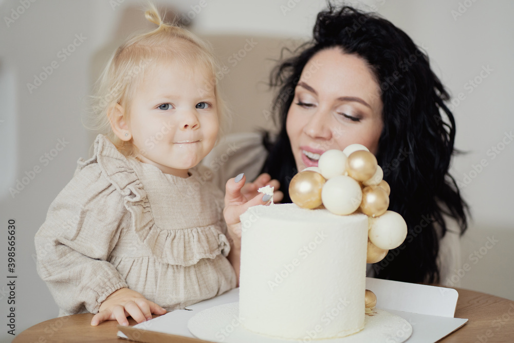Birthday of a little blonde girl, celebrating with her parents mom young brunette woman bought a big delicious healthy cake without sugar. Birthday of a little blonde girl, celebrating with her parents mom young brunette woman bought a big delicious healthy cake without sugar.