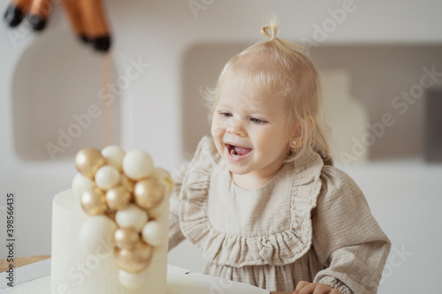 he eats a cake from his favorite pastry shop. A beautiful little blonde girl with a ponytail celebrates the holiday. Healthy home-made cheesecake cake mom. Dress beige color