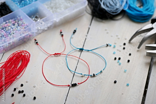 Handmade blue and red nylon cord bracelets with small beads over wooden background