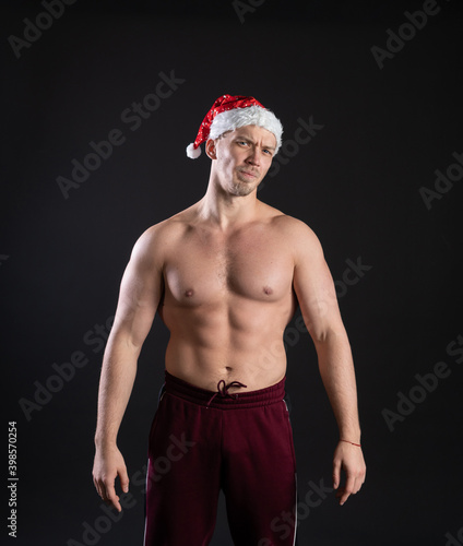 Santa Claus. Fitness bitseps  charming and graceful on a black background. In a red cap  on Christmas holidays with tender lips.