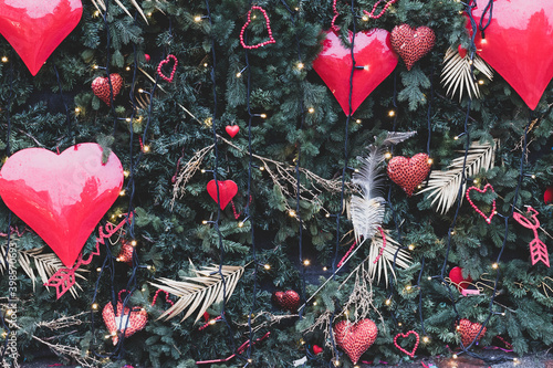 Green spruce branches decorated for Christmas with Christmas decorations in the shape of hearts. Matte toning.