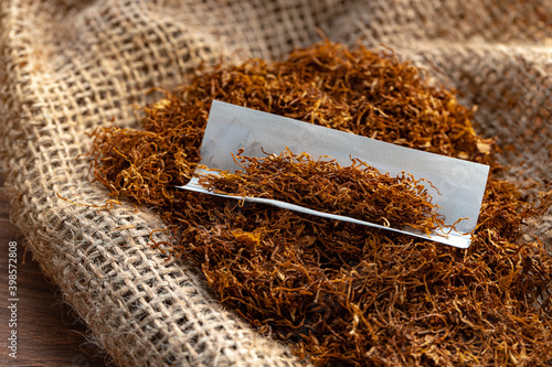 Cigarette paper and pile of tobacco on wooden table photo