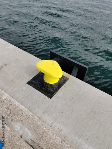 Yellow bollard mooring on the harborb wall