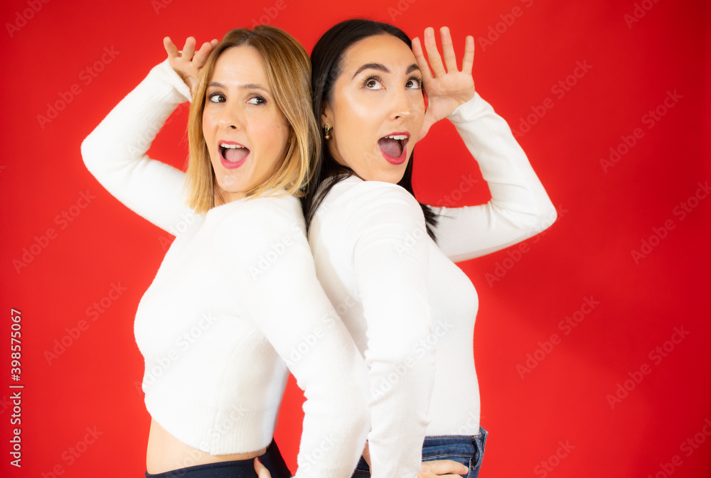 Beautiful women very surprised posing in against red wall, excited girls in white sweater. Beautiful women very surprised posing in against red wall, excited girls in white sweater.