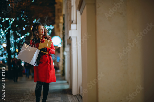 happy woman looking at shop window outdoors in city in evening