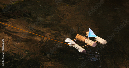 Fotografie A homemade toy sailing raft made from wine corks and toothpicks floats on a bubb