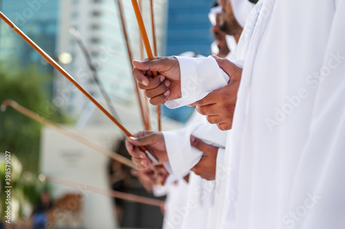 Traditional Emirati Al Ayala male dance, hands in frame holding bamboo canes. UAE heritage and unity concept.