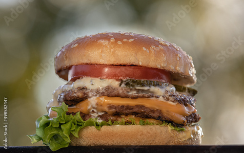 Tasty humburger with tomatoes and onion. Wooden background.  photo