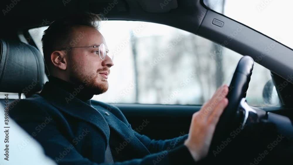 male driver in business clothes and glasses drives a car in winter city. male driver in business clothes and glasses drives a car in winter city.