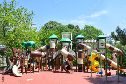 Colorful and modern children playground equipment in public park. Children activities at outdoor. Swing and seesaw. Empty playground during Covid-19 pandemic. Lockdown.