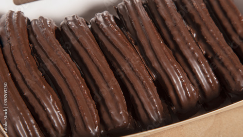 Closed up image of traditional Spanish fried dough churros with chocolate glaze served in a box