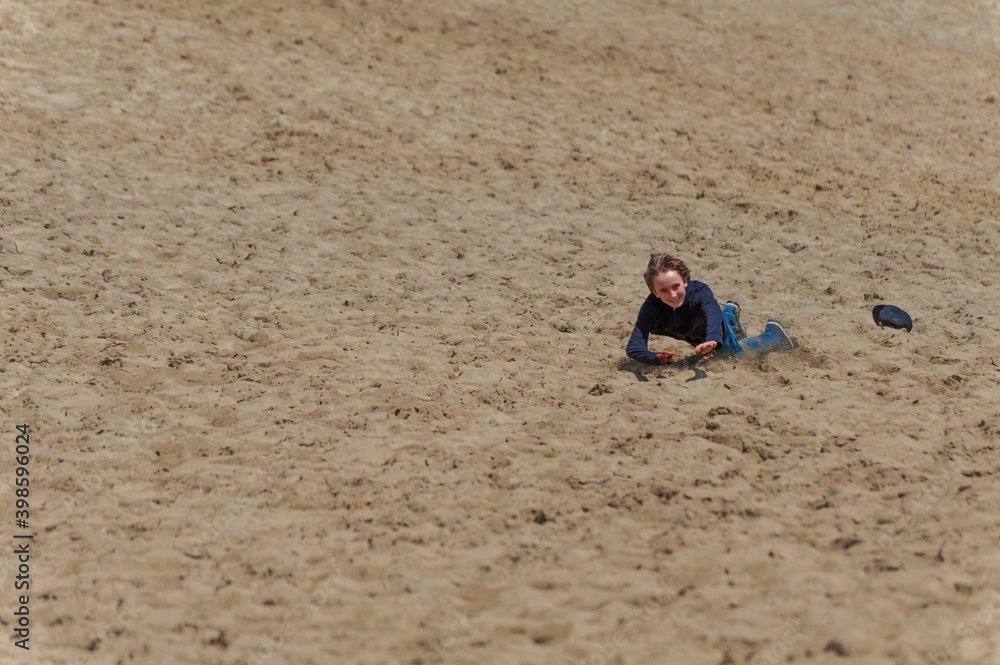 Boy plays on large sand dune hill at Pacific City on Oregon Coast Boy plays on large sand dune hill at Pacific City on Oregon Coast