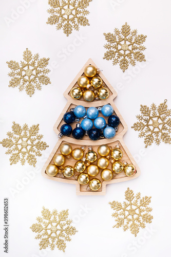 decorative blue and gold glass balls in a Christmas tree-shaped tray on a white background with snowflakes