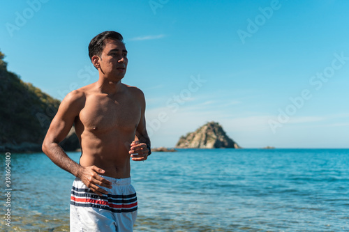 A male runner runs hard on the white sand of the beach during morning training