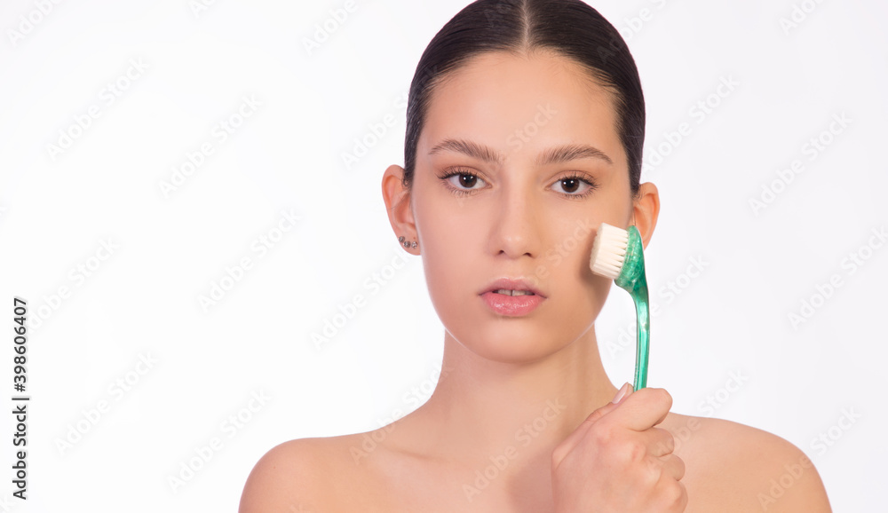 Girl with peeling brush for face on white background close up with copy space. Concept of healthy skin Girl with peeling brush for face on white background close up with copy space. Concept of healthy skin