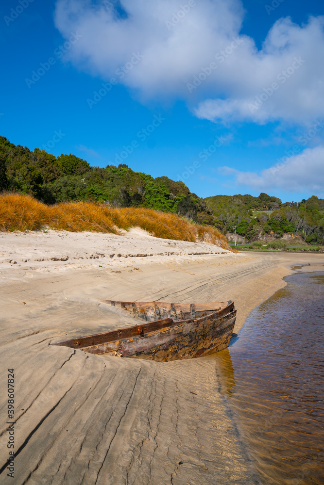 Lines and patterns curving along edge of stream interupted by bow of old wooden boat stuck in sand Lines and patterns curving along edge of stream interupted by bow of old wooden boat stuck in sand