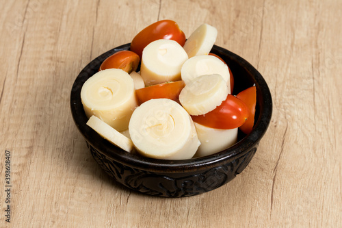 Simple and fresh palm heart or palmetto salad in a black bowl on a wooden table. photo