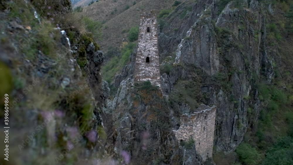 An old stone tower with windows on rock cliff. Historical stone tower static with grasses in foreground An old stone tower with windows on rock cliff. Historical stone tower static with grasses in foreground