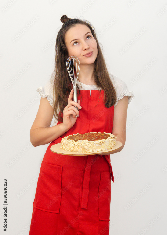a young woman brunette in a red apron holds a cake a young woman brunette in a red apron holds a cake