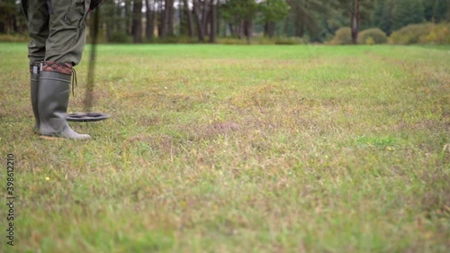Wallpaper Mural Man in boots treasure hunting with metal detector outdoors on the grass. Close up of man looking for coins in the ground Torontodigital.ca