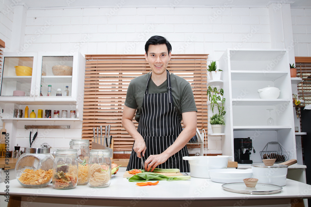 Asian men are happy to cook in the kitchen at home. Watching videos online learning through smartphones. Food concept. copy space Asian men are happy to cook in the kitchen at home. Watching videos online learning through smartphones. Food concept. copy space