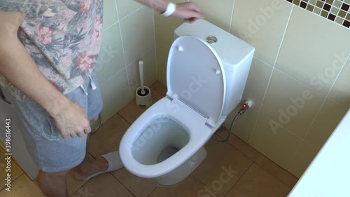 The man lowers the toilet seat and flushes the water