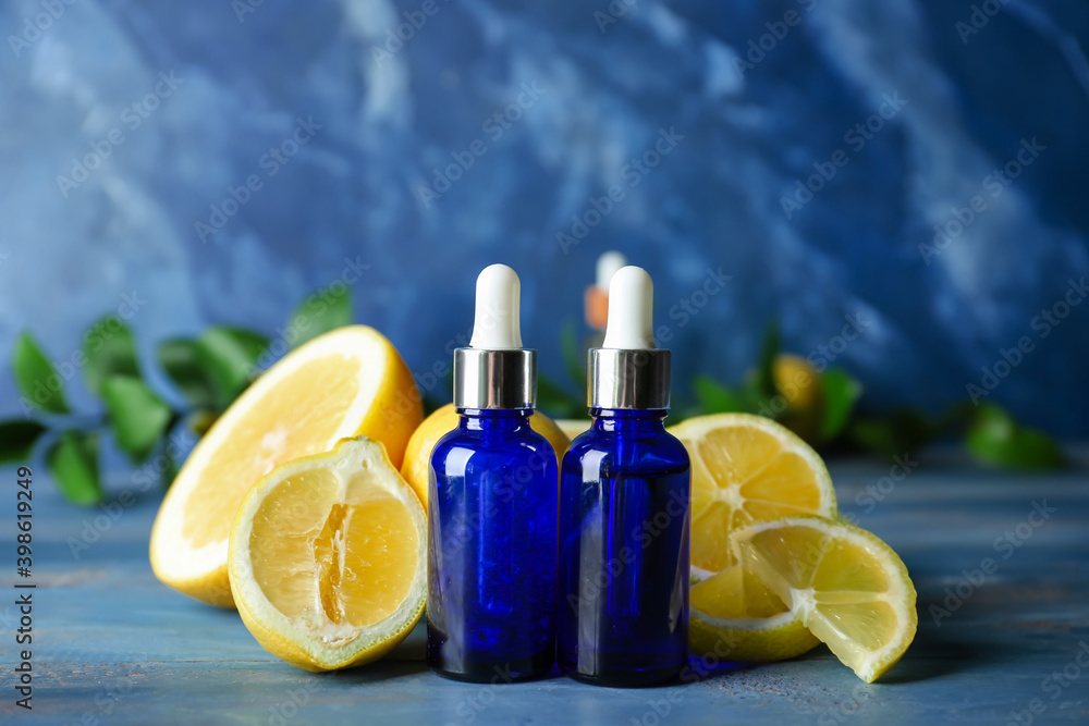 Bottles of lemon essential oil on color background Bottles of lemon essential oil on color background