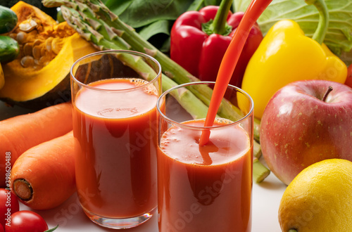 A lot of different kinds of vegetables and fruits on a white background and a glass of vegetable juice