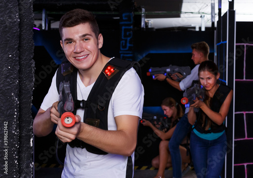 happy guy holding laser pistol playing laser tag game with his friends
