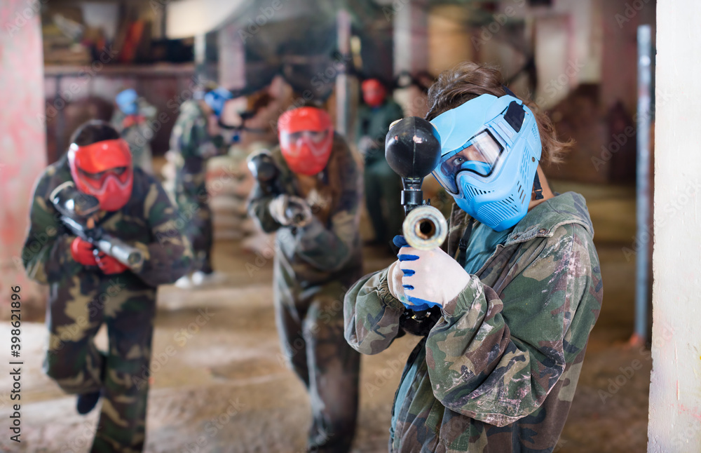 Portrait of player who is aiming in opponents while they are attacking in the paintball field