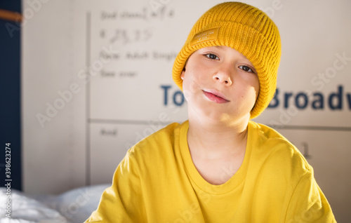 Boy in yellow tshirt and hat on blue two-tier bunk bed