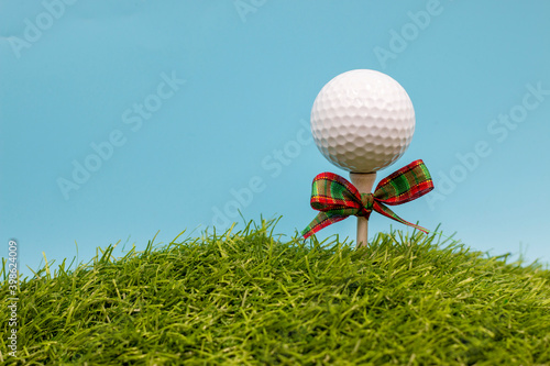 Golf ball with Christmas ribbon on blue sky background