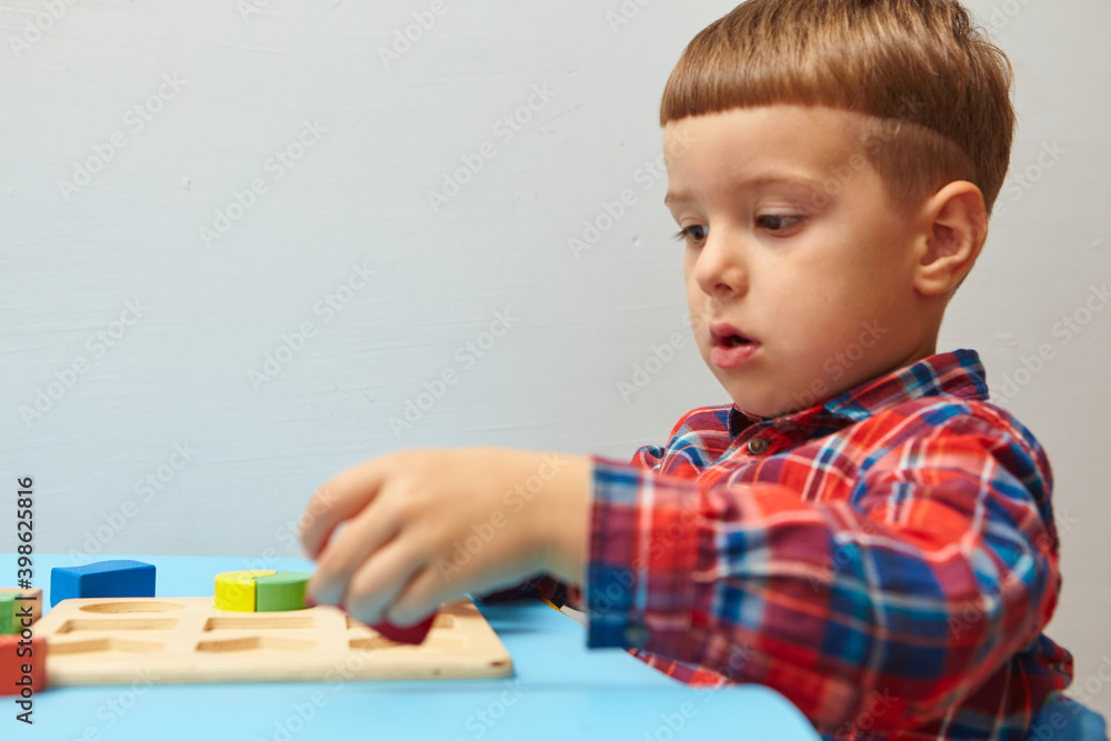 The boy is playing in his room. Learning shapes and colors. A child plays with a sorter. Educational logic toys for kid's. Montessori Games for Child Development.