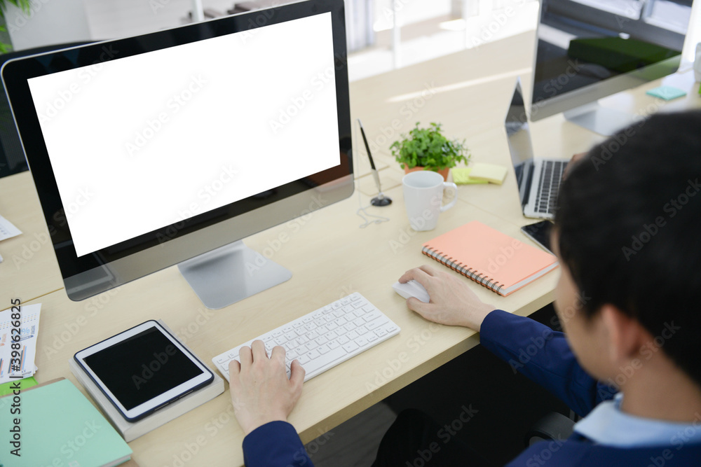 Mock up white screen of computer display with businessman working on the office desk Mock up white screen of computer display with businessman working on the office desk