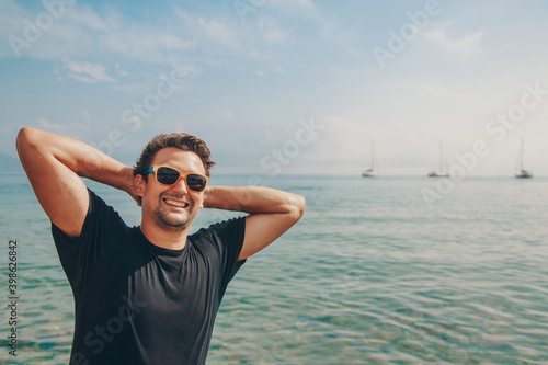 Canvas Print a contented man in sunglasses with his hands behind his head by the water