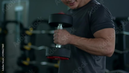 B-roll footage, muscular Asian young man lifting up a dumbbell in gym. Practice body and muscle building for a good body shape and poser.