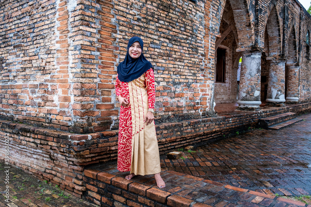 Fototapeta premium Happy attractive muslim woman travel in Pattani province, Thailand. Posing in courtyard of Mosque. Religion and tourist concept.