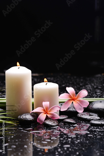 spa still life of with two  pink frangipani and green palm and two candle zen black stones  wet background 