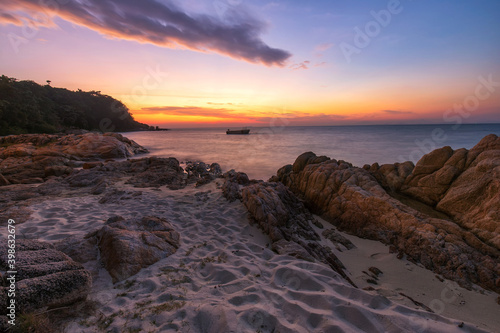 Beautiful tropical sea beach at sunset. Silky waves and rock on shore © surakit