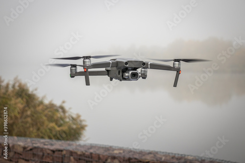a drone is flying at a small lake on a foggy autumn morning