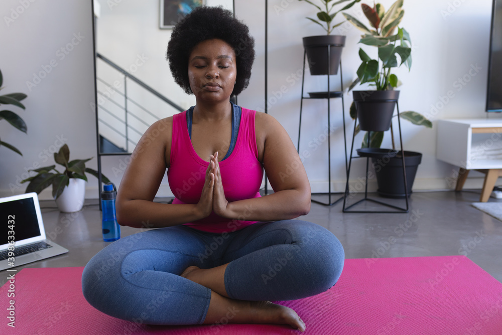 African american woman meditating sitting on mat wearing sports clothes African american woman meditating sitting on mat wearing sports clothes