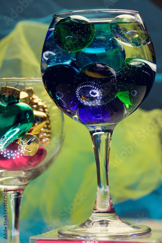 Two Champagne glass with a colorful glass balls and Christmas tree decorations inside. Abstract decorative element for restaurant and cafe menu or web design.